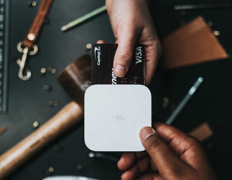 person holding Visa card and white device